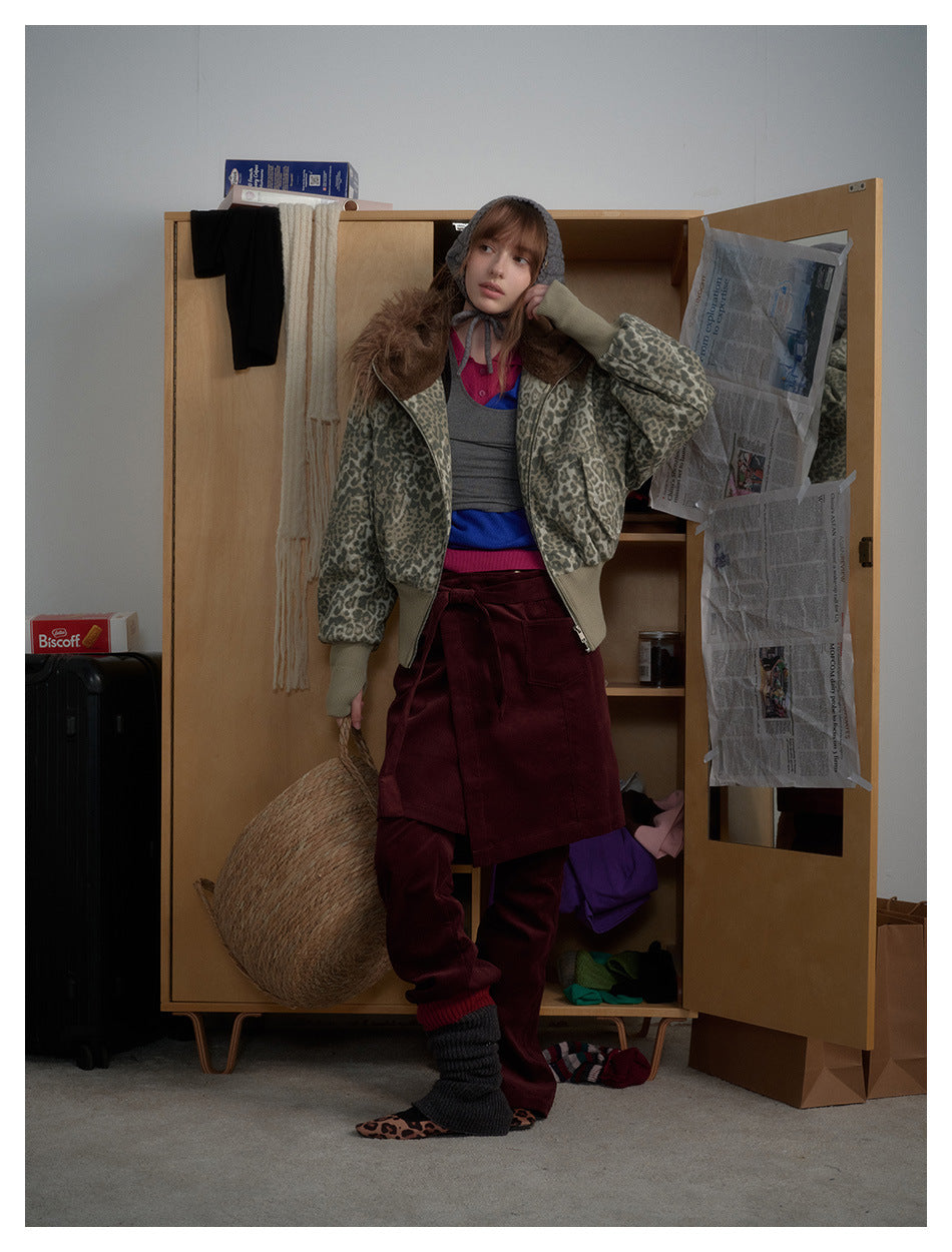Model wearing the leopard print hooded jacket with a burgundy skirt and pants, standing by a wooden wardrobe