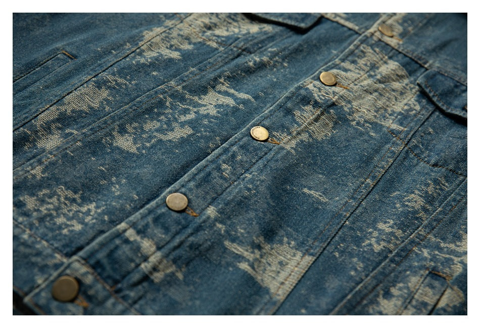 Angled close-up of a distressed blue denim jacket showing its button placket, pockets, and seams.