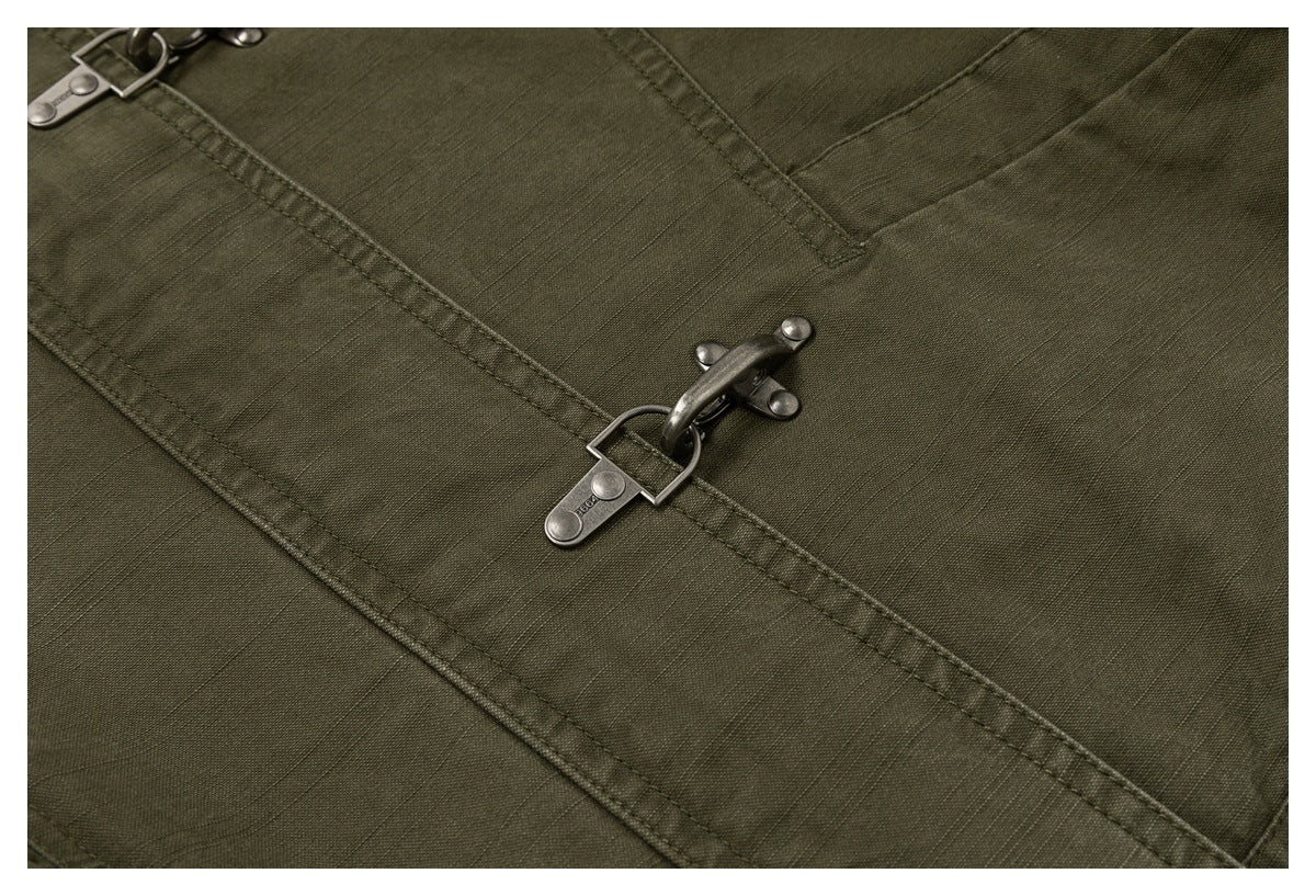 Close-up of the olive jacket's stitched fabric and metal hook-and-ring fastener.
