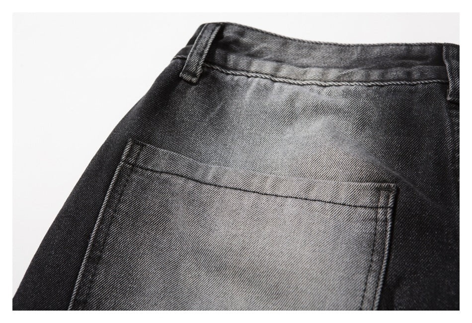 Close-up of a rear patch pocket and belt loop on faded black-gray denim jeans.