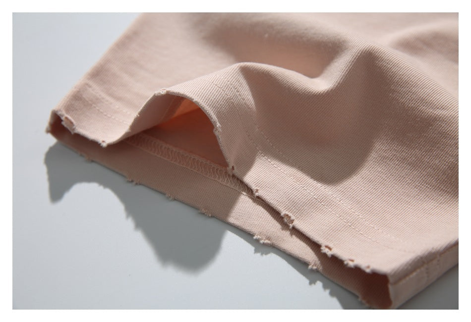 Close-up of the pale blush-pink T-shirt hem, showing its stitched edge and small frayed spots.