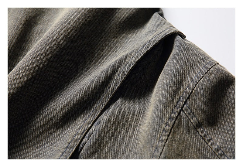 Close-up of a stitched opening and seam on mottled gray-olive garment fabric.