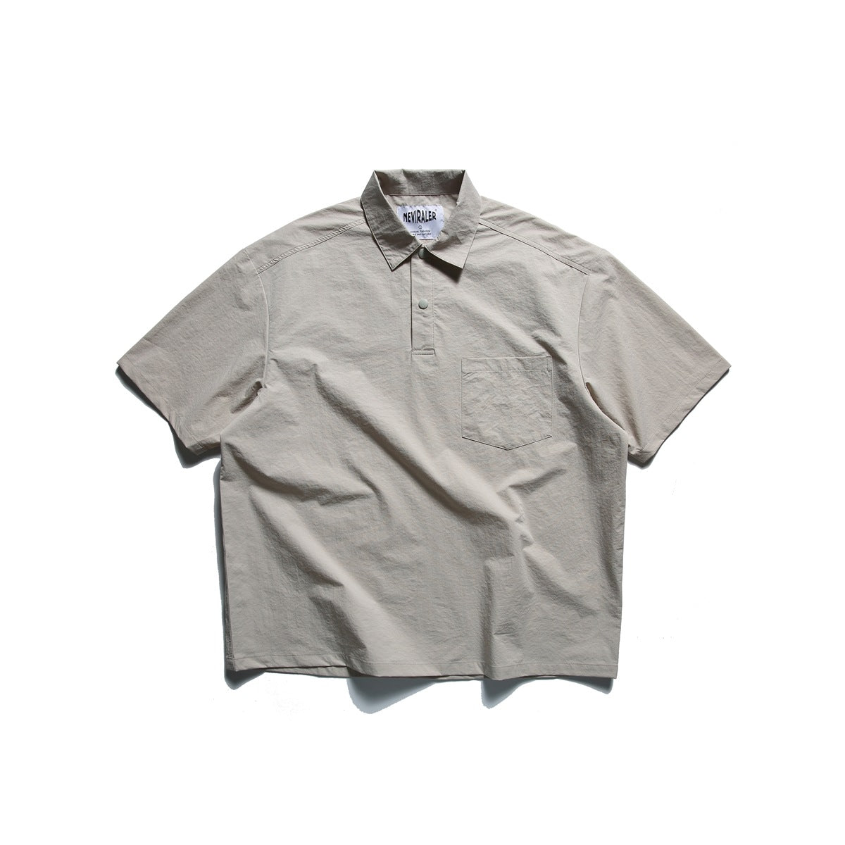 Light gray-beige short-sleeve polo-style top flat lay with snap half placket and chest pocket