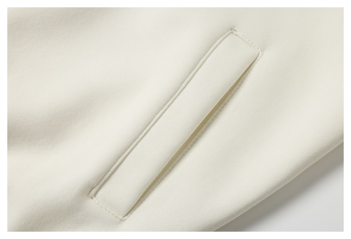 Close-up of an ivory garment with a long narrow stitched fabric strip.