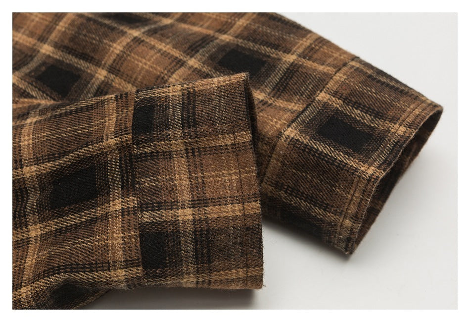 Close-up of the brown and black plaid shirt's folded cuff and sleeve seam.