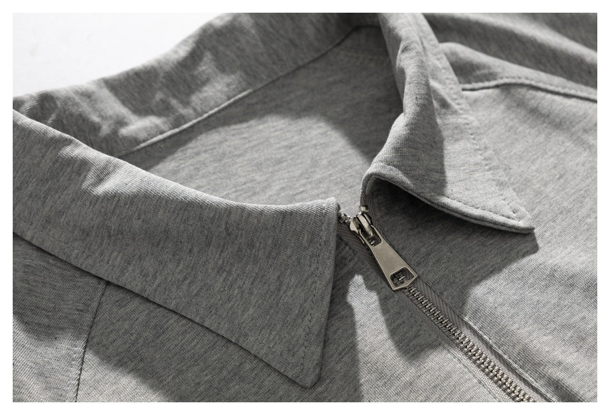 Close-up of a gray garment's folded collar and metal front zipper.