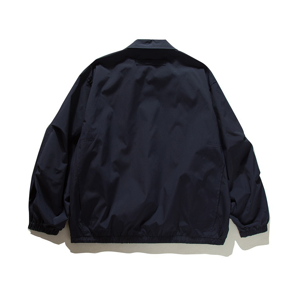 Back view of a dark navy collared jacket with long sleeves, elastic cuffs, and a gathered hem.