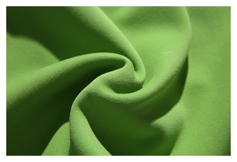 Close-up of bright green fabric draped in soft folds, showing its fine surface texture.