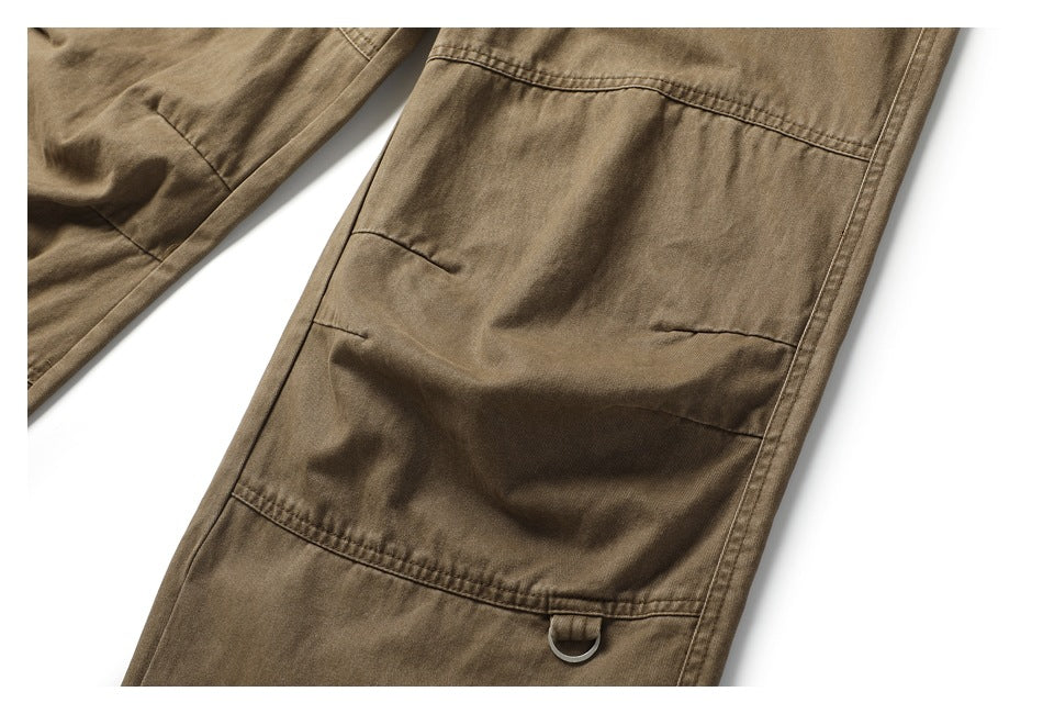 Close-up of a large stitched utility pocket and metal loop on the khaki-brown pants leg.