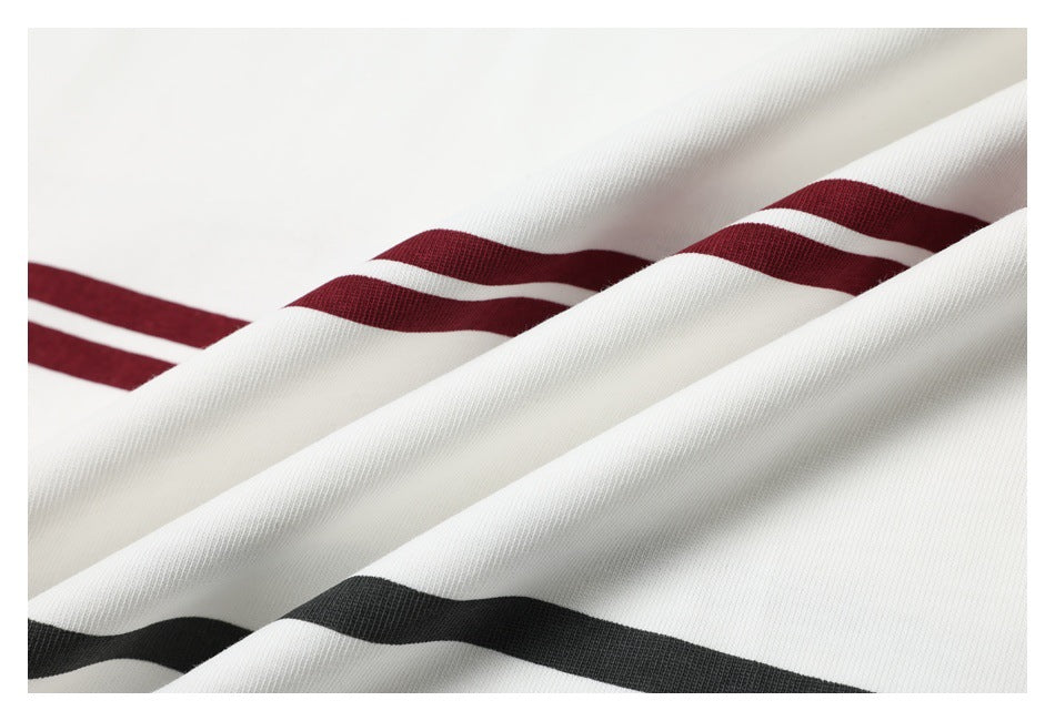 Close-up of white fabric draped to show burgundy double stripes and a black stripe.