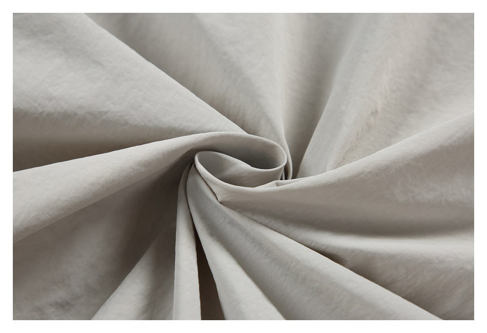 Close-up of light gray fabric gathered into soft folds to show its surface and drape.
