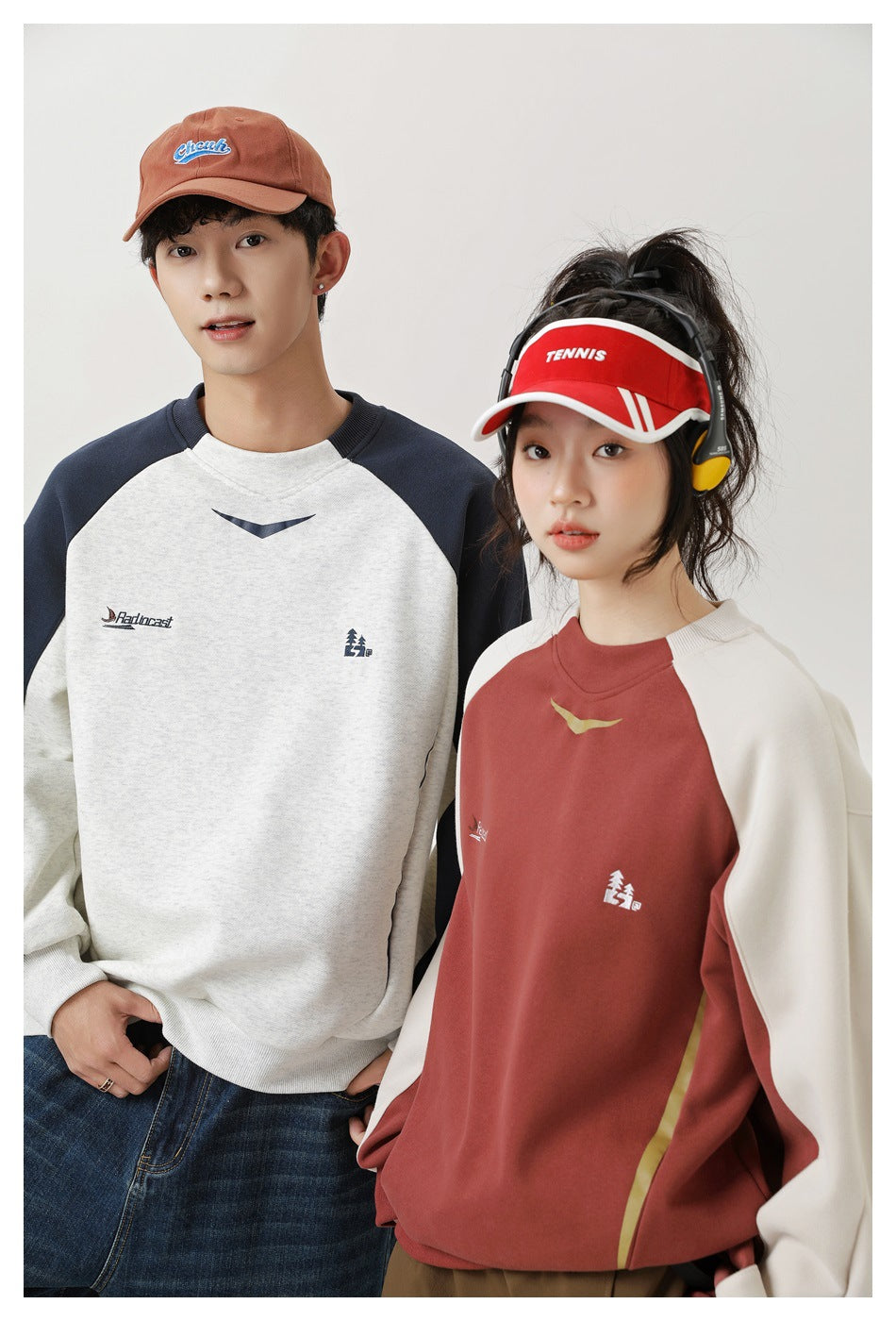 Two models pose in cream-and-navy and rust-and-cream color-block raglan sweatshirts, shown from the front.