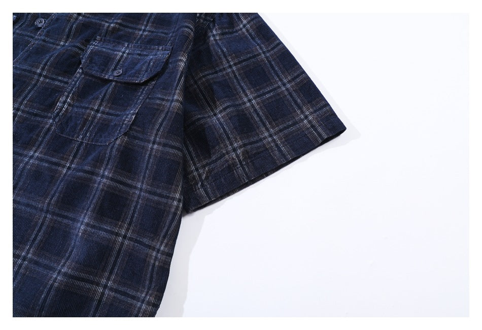 Close-up of a dark navy plaid short-sleeve shirt with a buttoned chest pocket.