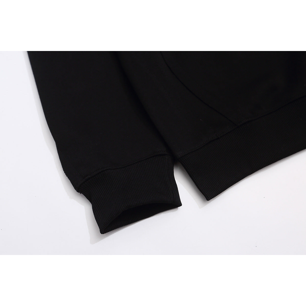 Close-up of a black sweatshirt’s ribbed sleeve cuff and bottom hem.