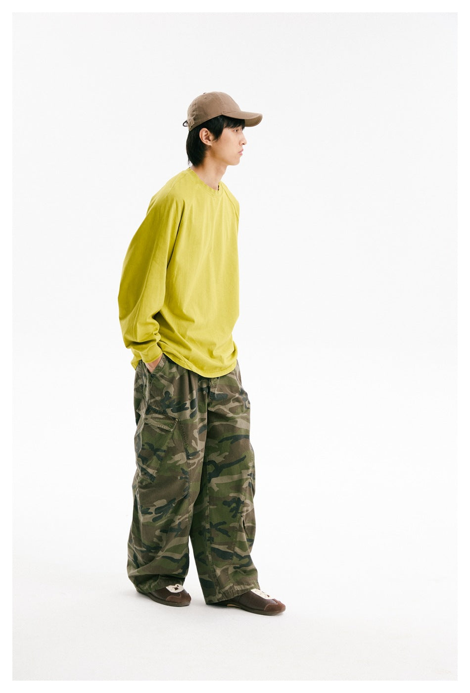 Side view of a model wearing a bright yellow-green oversized long-sleeve raglan shirt.
