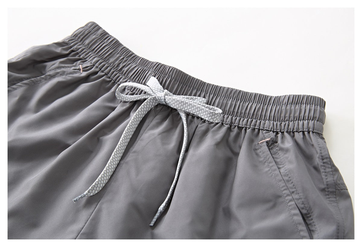 Gray shorts waistband with a white patterned drawstring, front pocket openings, and small pink accents.