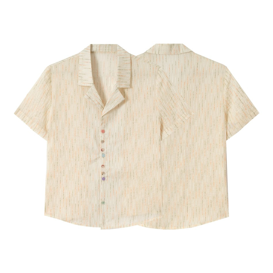 Flat-lay views of an ivory short-sleeve shirt from the front and back, with a notched collar and colorful buttons.