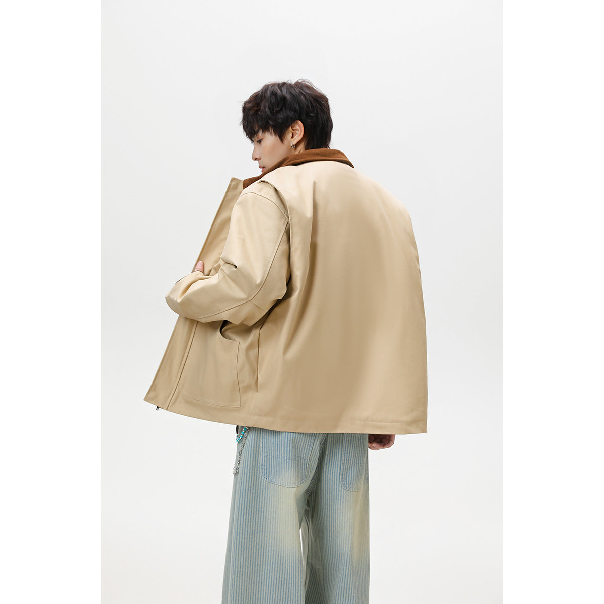 Model shown from behind wearing an oversized beige jacket with a brown collar and a large back panel.
