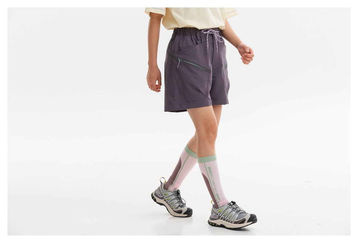 Side view of a model wearing dark plum drawstring shorts with large angled zip pockets.