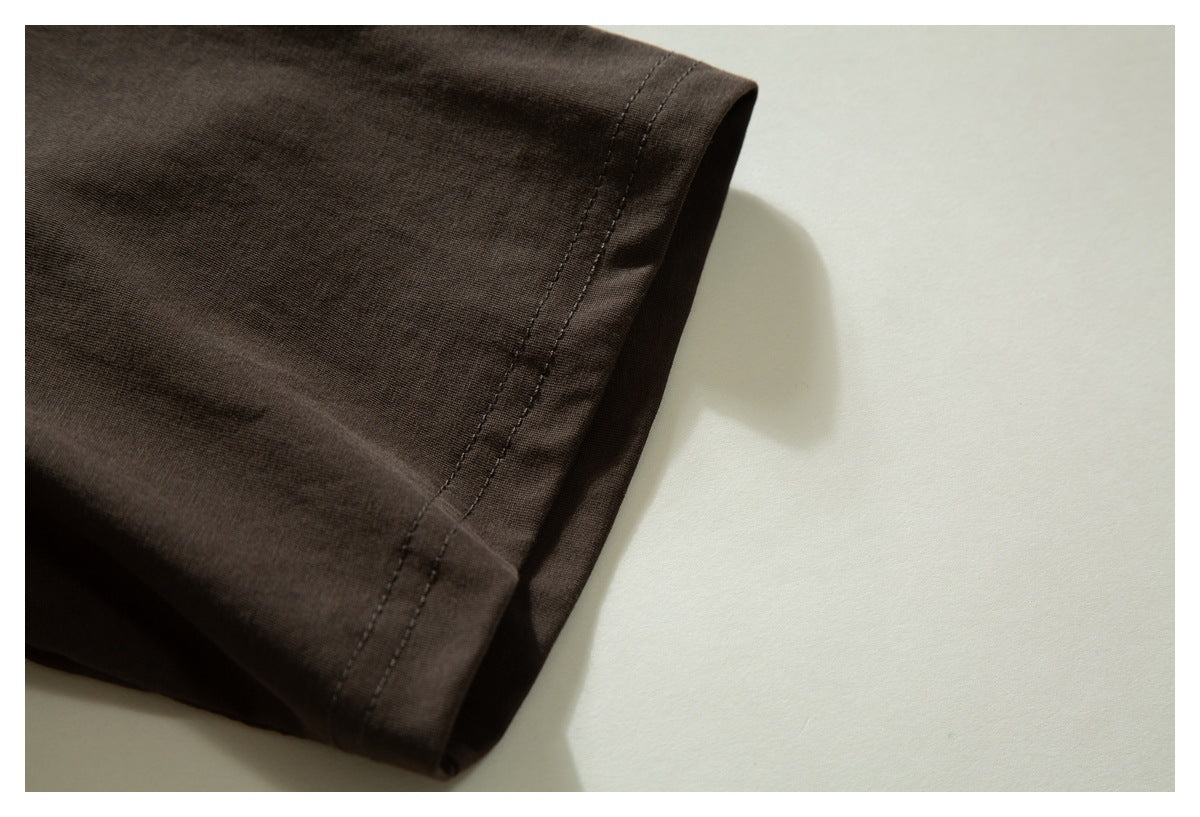 Close-up of the dark brown T-shirt sleeve and double-stitched hem.