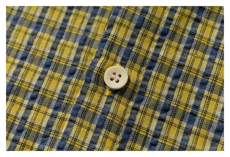 Close-up of a cream button on yellow and navy plaid fabric.