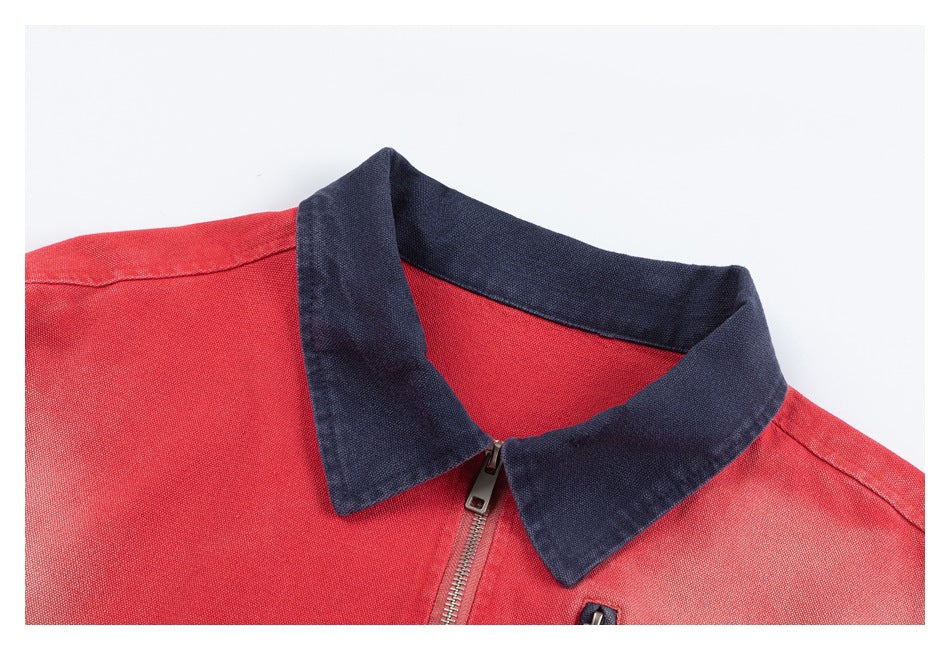 Close-up of a coral-red jacket with a dark navy collar and silver front zipper.