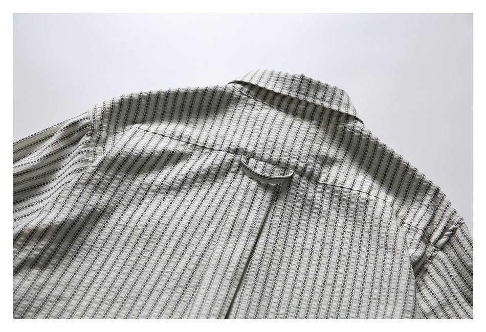 Upper back of a cream shirt laid flat, with a pointed collar and narrow black geometric stripes.