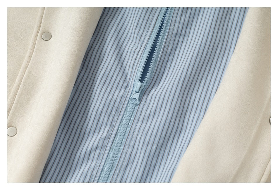 Close-up of a pale blue zipper on a narrow blue-and-gray striped panel between cream garment sections.