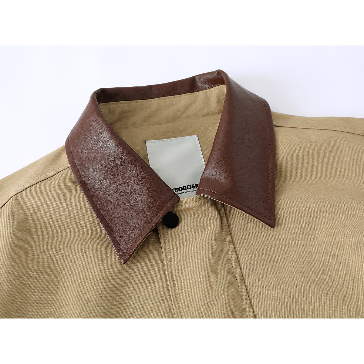 Close-up of a tan jacket with a wide dark brown collar, concealed placket, and black snap.