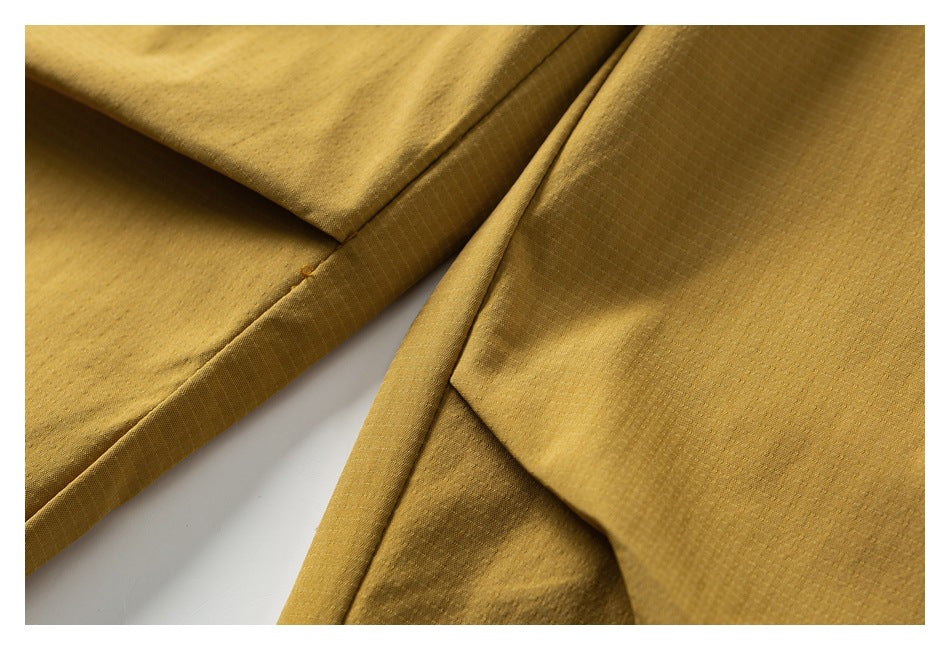 Close-up of mustard-gold trousers showing a stitched seam and folded fabric.