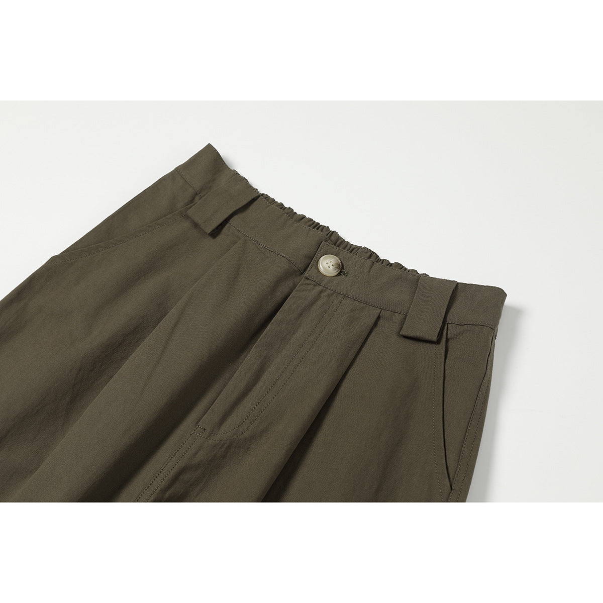 Close-up of dark olive trousers showing the front waistband, button, belt loops and pleats.