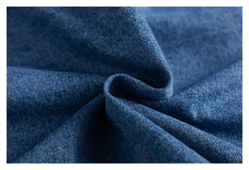 Close-up of blue denim fabric folded into soft curves, showing its woven texture.