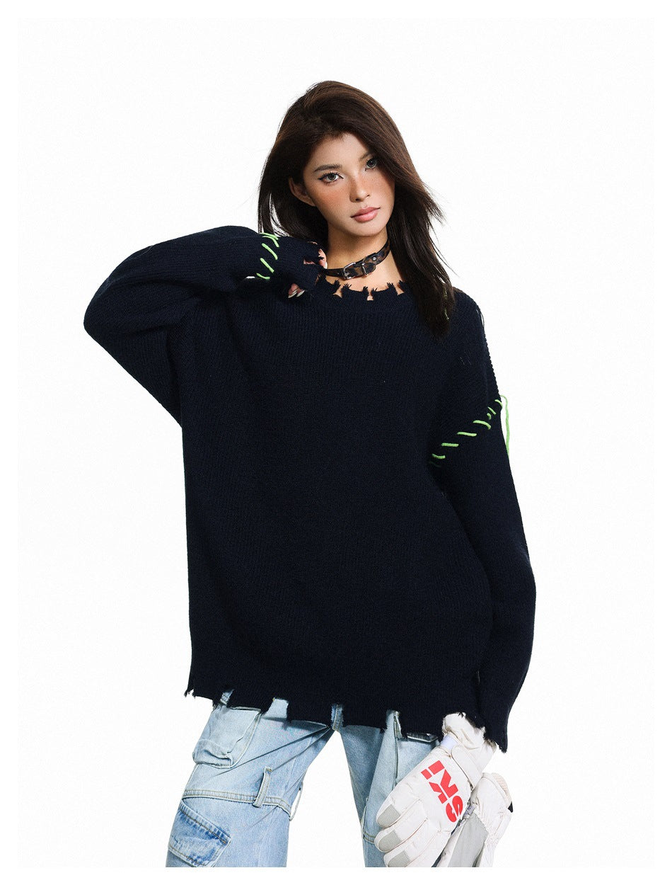 Model wearing an oversized dark navy sweater with a distressed neckline and hem and bright green contrast stitching.