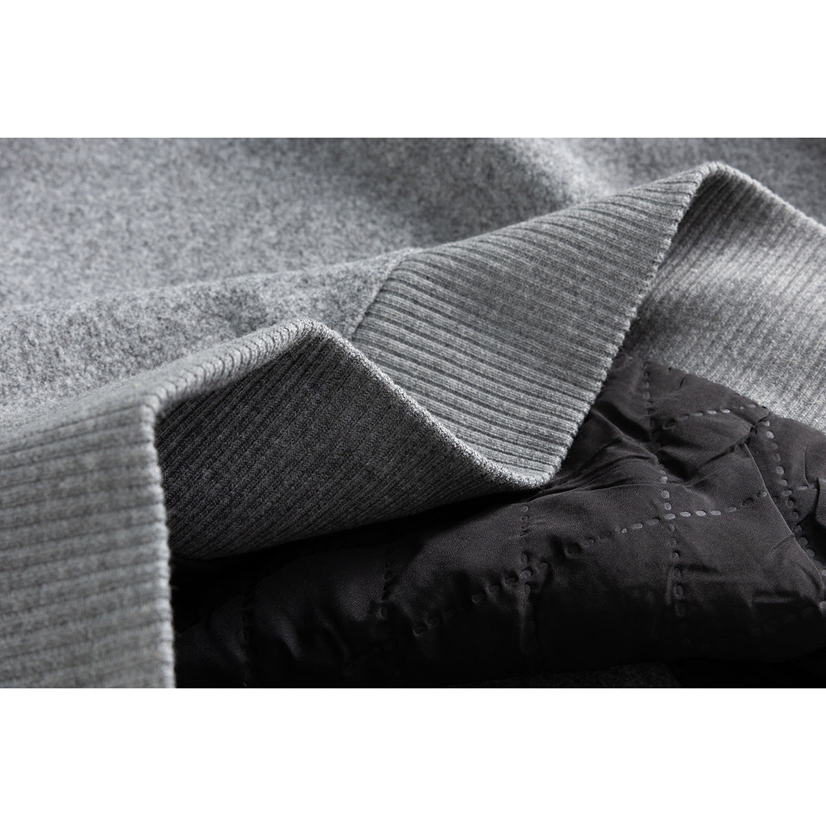 Close-up of the gray jacket's ribbed cuff and dark quilted inner lining.