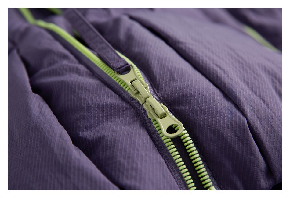 Close-up of a lime-green two-way zipper on a dark purple garment with fine vertical texture.