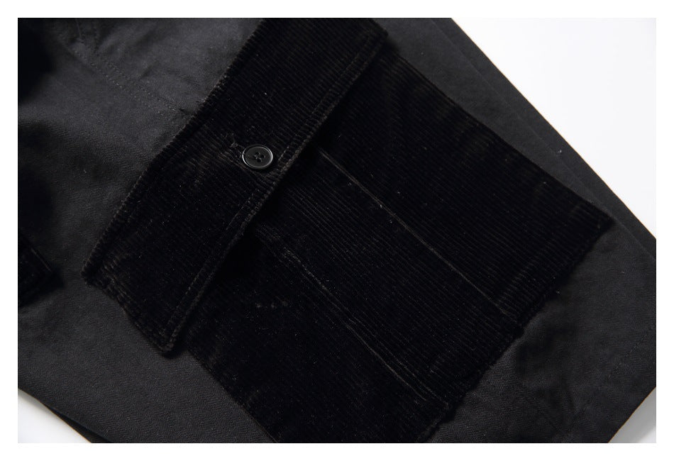 Close-up of a black shorts pocket with a ribbed flap, button, and matching panel.