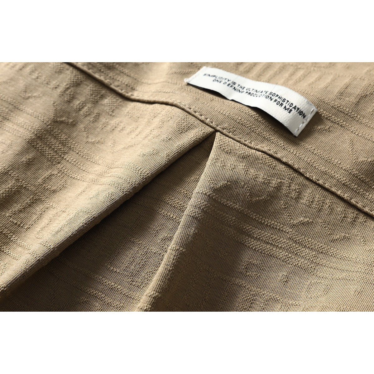 Close-up of the tan shirt’s fabric, seam and small white interior label.