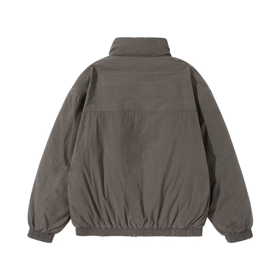Back view of a charcoal gray jacket laid flat, with a high collar, long sleeves, and gathered cuffs and hem.