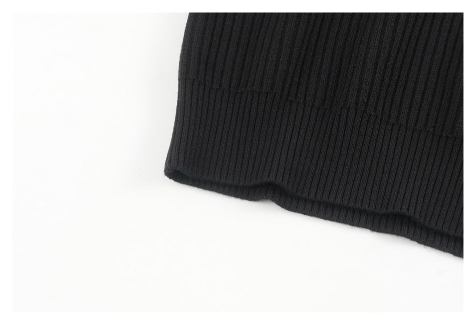 Close-up of the black ribbed sweater's ribbed bottom hem and vertical knit pattern.