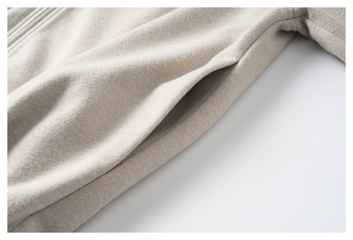 Close-up of a seam and folded edge on beige heathered fabric against a white background.