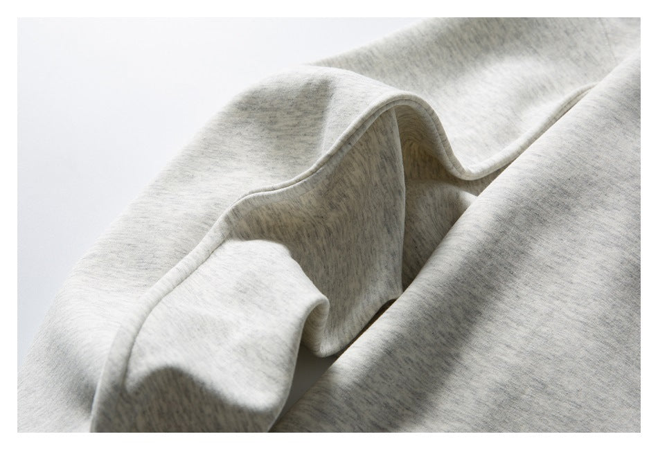 Close-up of light gray heathered fabric draped in soft folds, showing a finished curved edge.