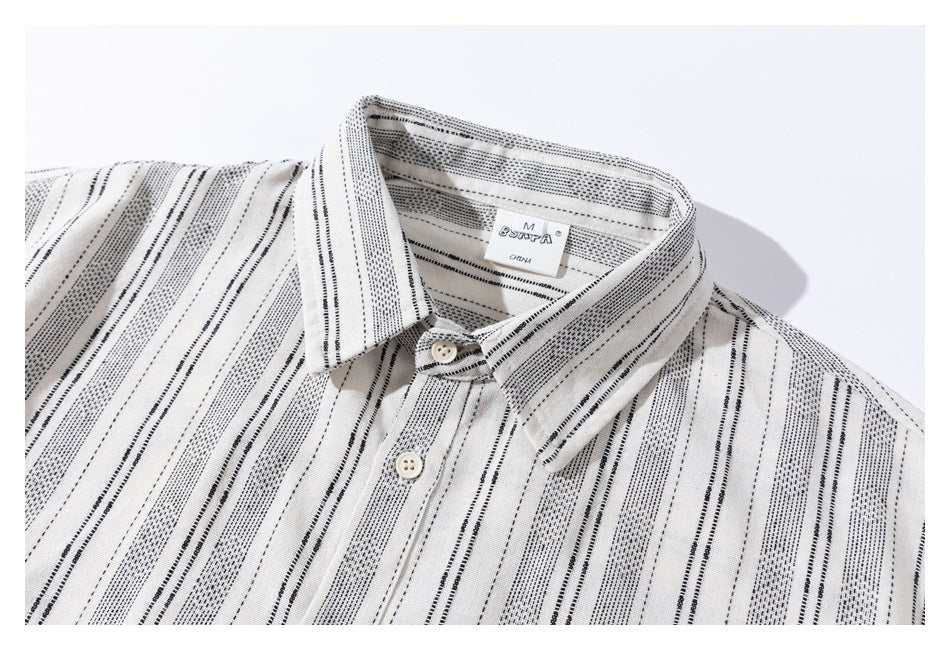 Close-up of a cream shirt collar and placket with narrow black stripe patterns and a sewn-in neck label.