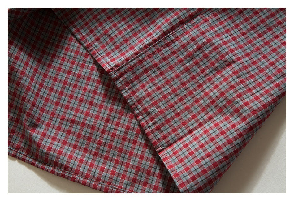 Close-up of overlapping sections and seams on a red, gray, and white plaid shirt.
