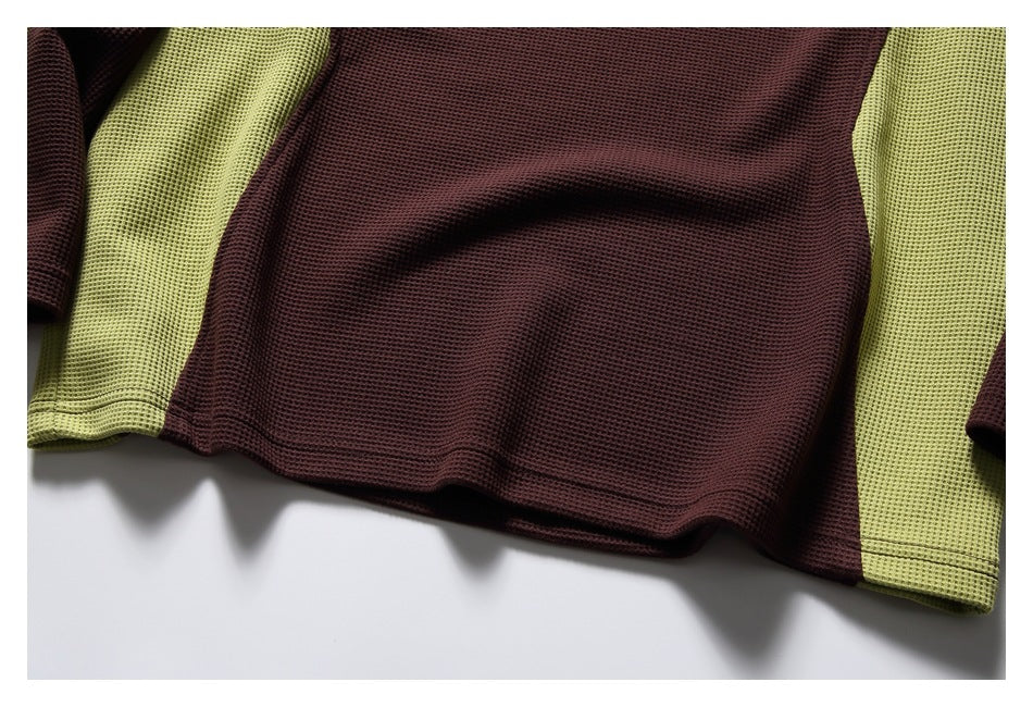 Close-up of the burgundy and lime-green top’s textured fabric and hem stitching.