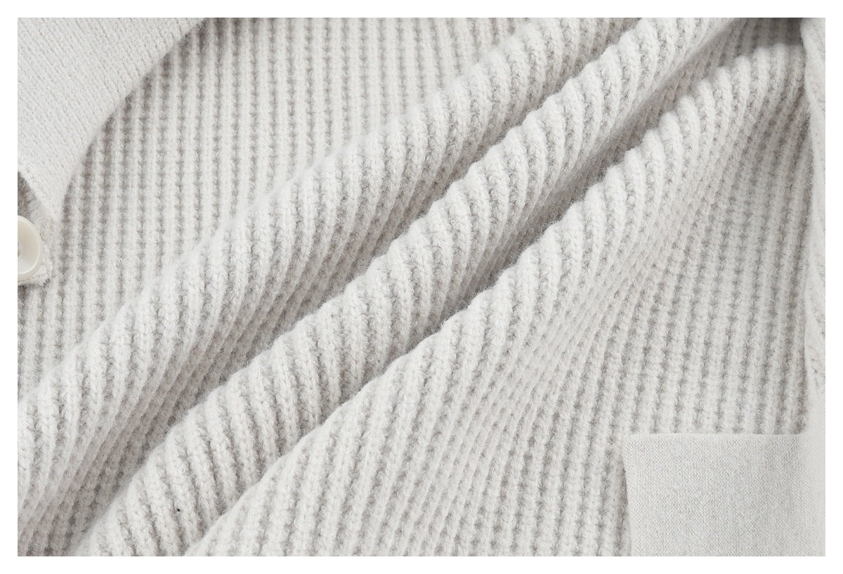 Close-up of a light gray cardigan's textured knit, button edge, and patch pocket.