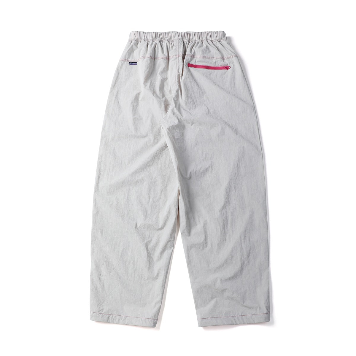 Back view of loose off-white trousers with an elastic waistband and a bright pink horizontal zip pocket.