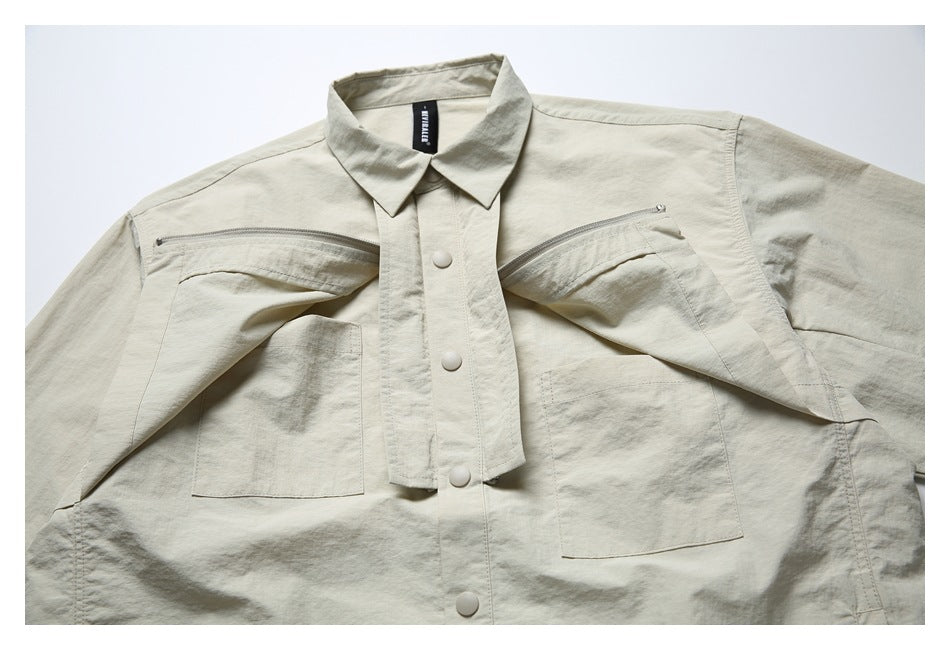 Front flat lay of a light beige shirt jacket with a pointed collar, snap buttons, two chest zippers, and patch pockets.