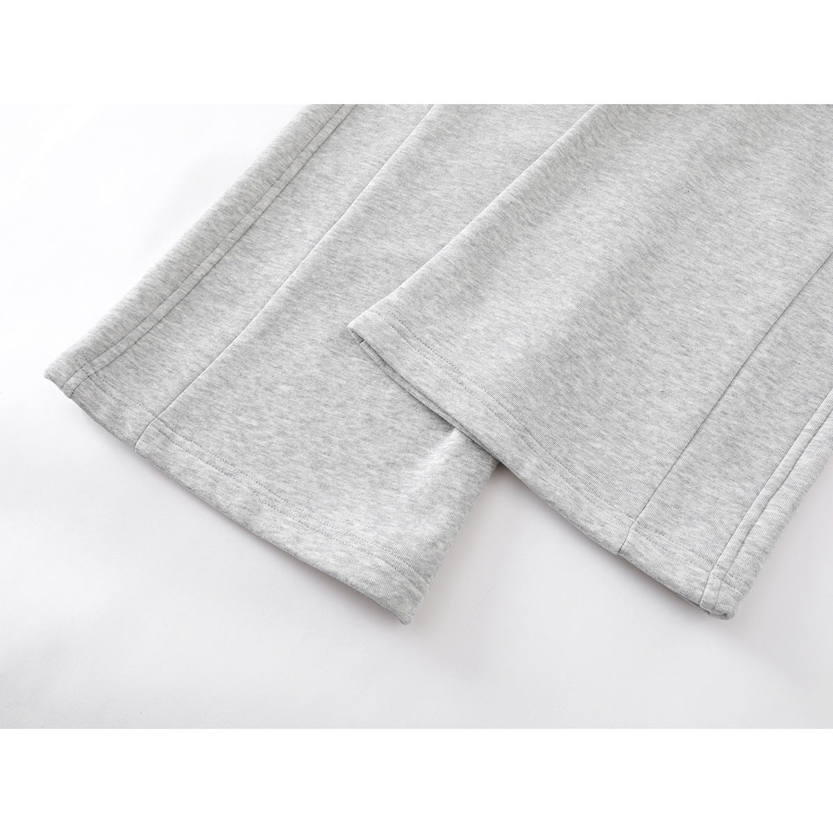 Close-up of the wide, stitched hems on light gray sweatpants.
