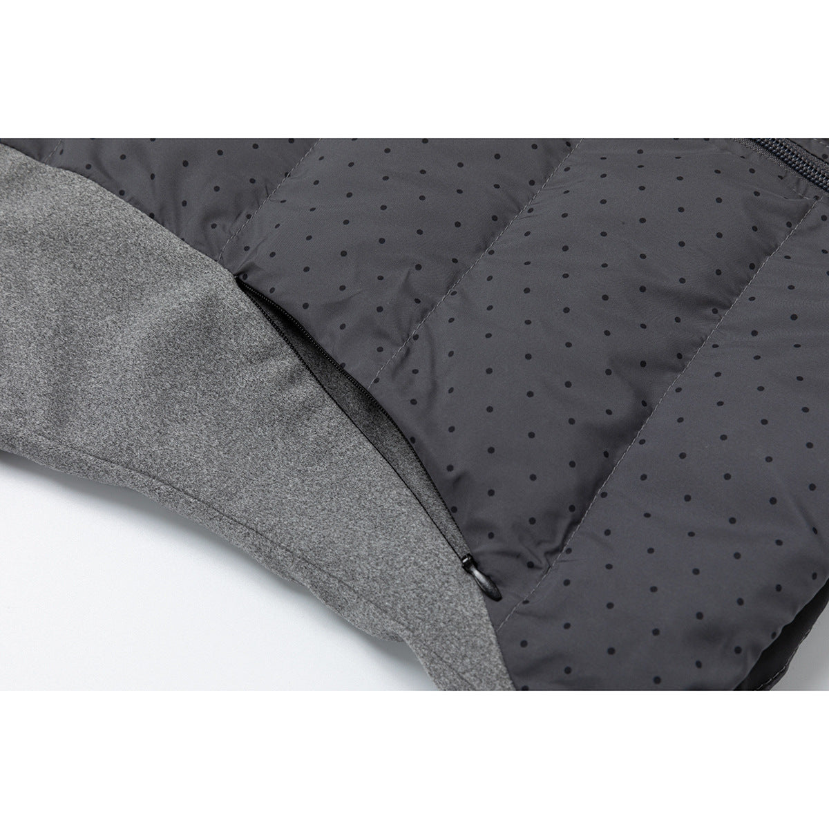 Close-up of a black side zipper between the gray sleeve and charcoal dotted jacket panel.