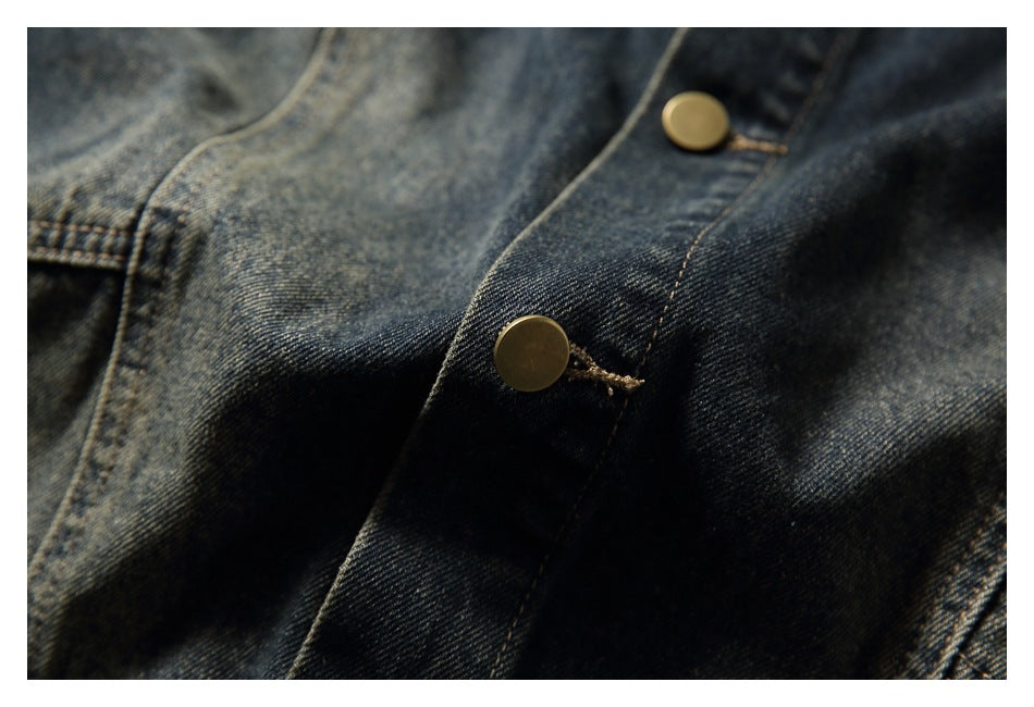 Close-up of brass-tone snap buttons and stitching on the dark denim jacket front.